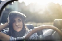 Giovane donna che indossa un cappello piatto in auto convertibile — Foto stock