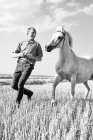 B & W imagem de treinador masculino correndo na frente de cavalo branco no campo — Fotografia de Stock