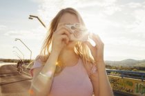 Молодая женщина на мосту фотографирует на цифровую камеру — стоковое фото