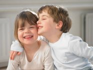 Lächelnde Kinder, die sich drinnen umarmen — Stockfoto