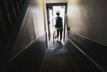 Jovem no fundo das escadas, saindo do prédio com bicicleta, vista elevada — Fotografia de Stock