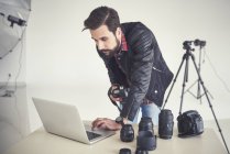 Fotógrafo masculino revisando sesión de fotos de estudio en portátil - foto de stock