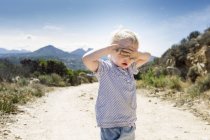 Female toddler on dirt track with hands covering eyes, Calvi, Corsica, France — Stock Photo