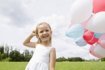 Menina segurando um monte de balões — Fotografia de Stock