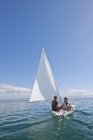 Dos jóvenes navegando hacia el agua de mar - foto de stock