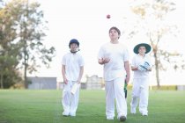 Three boys walking on cricket pitch — Stock Photo