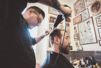 Barber drying client hair in barber shop — Stock Photo
