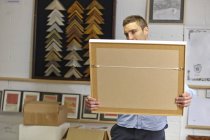 Мужчина осматривает рамку в мастерской для картин — стоковое фото
