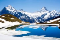 Snowy landscape reflected in lake — Stock Photo