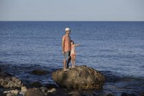 Отец и дочь стоят на скалах в море, Коста Брава, Каталония, Испания — стоковое фото