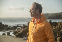 Reifer Mann, der am Strand steht und aufs Meer blickt — Stockfoto