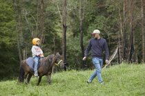 Padre con hija montando pony, Valle de Aran, España - foto de stock