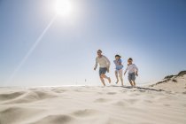 Отец и сыновья бегут по пляжу — стоковое фото
