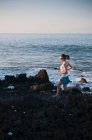 Mujer corriendo en la playa rocosa - foto de stock