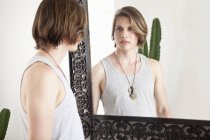 Young man looking at mirror image in hotel lobby — Stock Photo