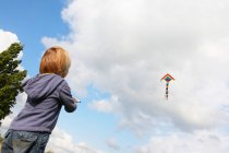 Boy flying kite outdoors, low angle view — Stock Photo