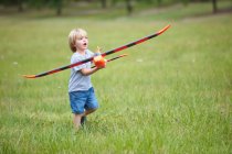 Мальчик играет с игрушечным самолетом на открытом воздухе — стоковое фото