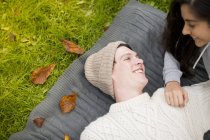 Jeune couple allongé sur un tapis, homme portant un chapeau en tricot — Photo de stock