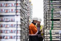 Workers inspecting stacks of aluminium ingots in warehouse — Stock Photo