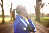 Femme mature coureuse dans le parc ajustement écouteurs — Photo de stock