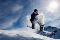 Male snowboarding on snow caped mountain descent — Stock Photo