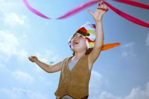 Toddler in Indian headdress with ribbon against blue sky — Stock Photo