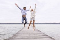 Ehepaar springt vor Freude auf Seebrücke — Stockfoto
