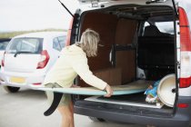 Femme âgée mettant planche de surf en van ouvert — Photo de stock