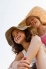 Chicas sonrientes usando sombreros al aire libre - foto de stock