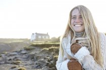 Счастливая молодая женщина, завернутая в шарф на пляже, залив Константин, Корнуолл, Великобритания — стоковое фото