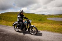 Hombre mayor en moto en carretera rural - foto de stock