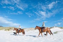 2 people riding horses on the beach — Stock Photo