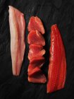 Raw fish fillets on dark wood, top view — Stock Photo