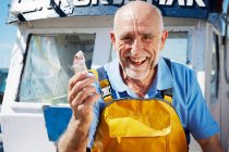 Улыбающийся рыбак с рыбой в руках — стоковое фото