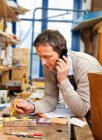 Carpenter talking on phone in shop — Stock Photo