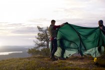 Excursionistas construyendo tienda de campaña en viajes, Laponia, Finlandia - foto de stock