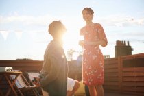 Man proposing to woman on roof terrace, sunset in background — Stock Photo
