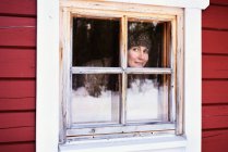 Porträt einer jungen Frau, die aus dem Kabinenfenster blickt, posio, Lappland, Finnland — Stockfoto