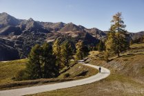 Ciclista en carretera con montañas a lo lejos, Valais, Suiza - foto de stock