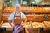 Жінка-пекар посміхається на камеру в магазині — стокове фото