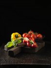 Peppers, tomatoes and basil on wooden board — Stock Photo
