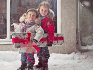 Children with Christmas present in snow — Stock Photo