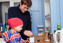 Pai fazendo xícara de chá com filho na cozinha — Fotografia de Stock