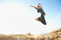 Smiling teenage girl jumping on beach — Stock Photo