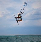 Kitesurfer saltando en el aire y haciendo truco - foto de stock
