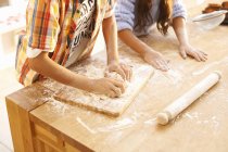 Cropped image of children making dough in kitchen — Stock Photo