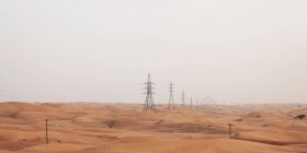 Pilones eléctricos en el desierto, Dubai, Emiratos Árabes Unidos - foto de stock