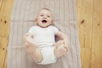 Ritratto di bambino sorridente sdraiato sulla coperta — Foto stock
