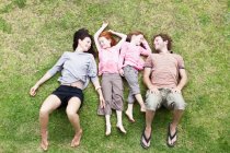 Famille couché dans l'herbe ensemble — Photo de stock