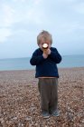 Boy with torch on pebble beach — Stock Photo